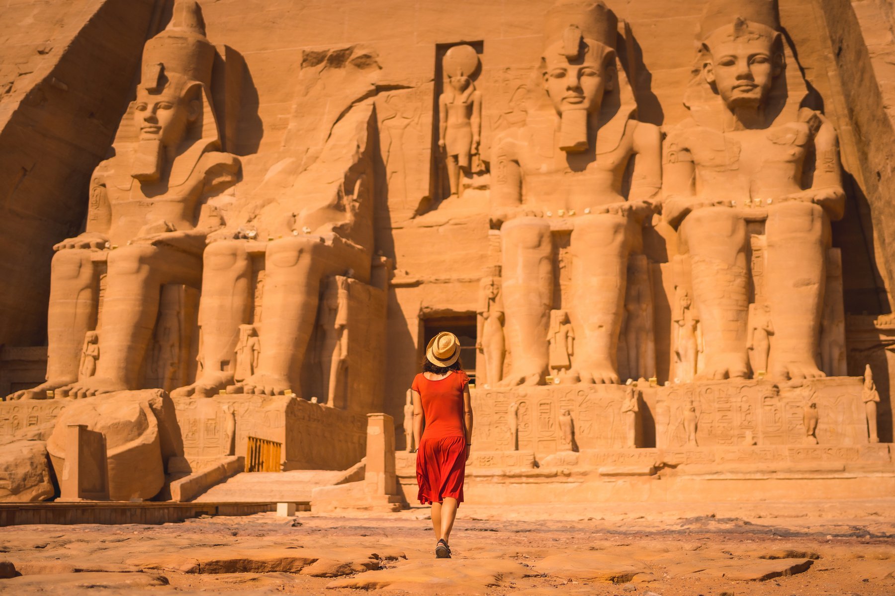 A young tourist in a red dress leaving the Abu Simbel Temple in southern Egypt in Nubia next to Lake Nasser. Temple of Pharaoh Ramses II